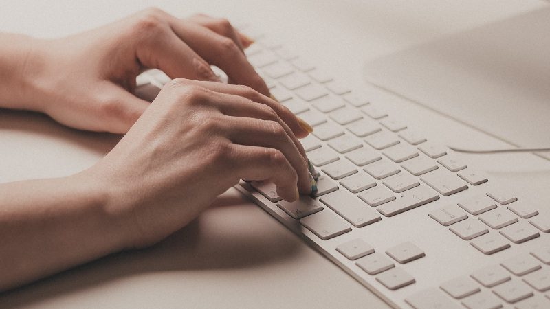 A person typing on a computer keyboard